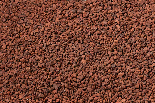 Close up of natural red volcanic rock scoria gravel texture for landscaping and garden mulch. Detailed view of porous lava stones background for decorative and drainage purposes.