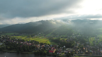 Obraz premium Morning fog above tranquil green hillside community