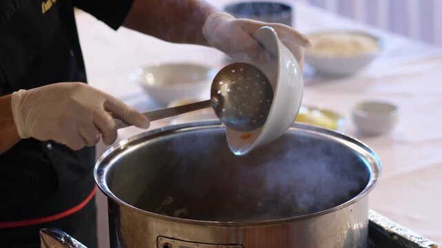 Freshly chopped carrots are poured into a hot pot where ingredients are cooking. The scene captures the moment vegetables are added, highlighting the layering of flavors during meal preparation.
