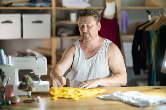 Middle-aged male dressmaker reviewing finished child dress