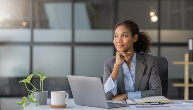 Focused Thoughts: A determined business woman gazes out of the window with her laptop on the desk, expressing contemplation and ambition, in a modern, well-lit office.