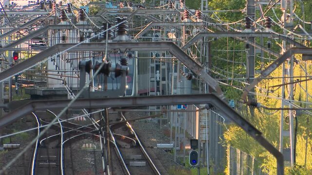 Commuter train traveling on railway tracks under catenary wires