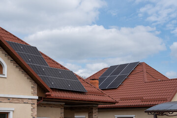 Fototapeta premium Solar panels on rooftops of residential houses. Concept of clean energy adoption, sustainable development and growing use of renewable energy in modern neighborhoods.