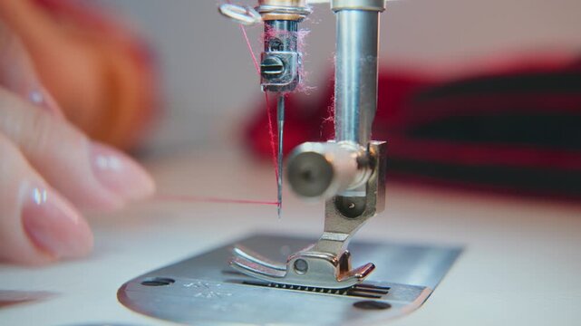 Close-up of hands guiding fabric under sewing machine needle. Focus on thread, presser foot, and steady motion. Soft lighting highlights craftsmanship and attention to detail. Ideal for fashion, DIY