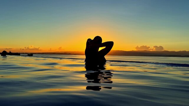 Silhouette of person in calm sea water at sunset with glowing horizon, Mactan Cebu, Philippines