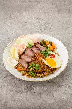 Delicious Bakmi Goreng with Sliced Beef, Fried Egg, and Crackers on White Plate