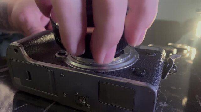 Hands installing lens adapter onto camera bayonet mount close-up, aligning metal ring, locking it into place on mirrorless body, demonstrating precise connection process, interchangeable lens systems