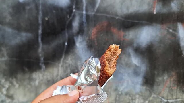 Crispy Chocolate Biscuit Snack in Hand Sweet Crunchy Cookie Close Up with Foil Packaging