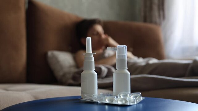 sick man lying in bed suffering virus having medicine tablets. drinking pill. A sick teenager lies on the couch, coughing and taking pills for a seasonal virus.