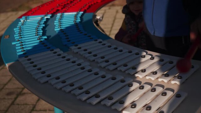 A musician creates melodic tones on a large, resonant xylophone. The instrument's wooden bars produce a vibrant, percussive sound.