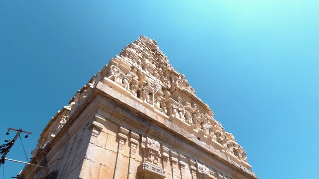 Upward view of ornate Yoga Narasimha Swamy temple tower with detailed carvings against clear blue sky in Melukote