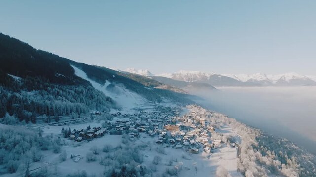 A snow-covered village at dawn, bordered by a vast mountain range. Ideal for winter-themed projects or travel content.
