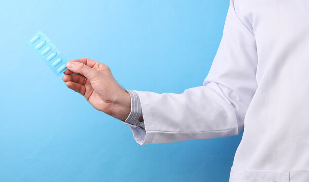 Doctor in a white medical coat holding rectal suppositories on a blue background