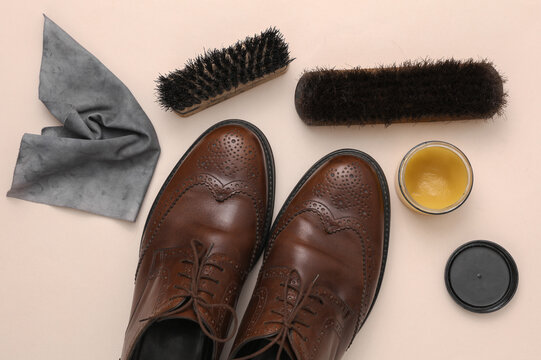Shoe care products and leather shoes on a beige background