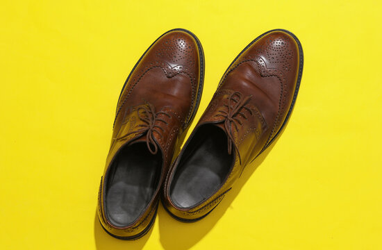 Man's Classic leather brown brogue shoes on a yellow background. Top view