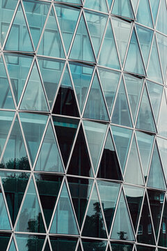 Teal glass building facade with triangles grid and geometry pattern showing modern architecture design for contemporary exterior background with windows