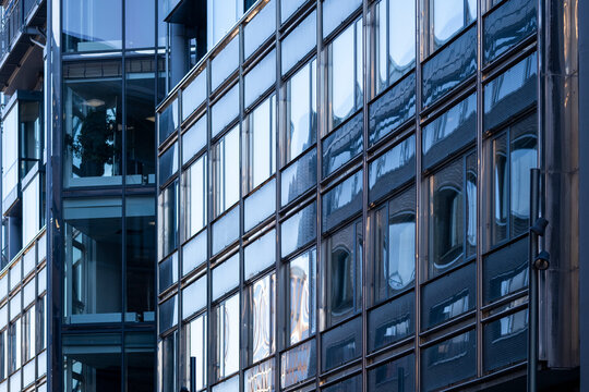 Urban office building with modern glass facade windows reflections and grid architecture pattern creating corporate business texture background in daylight