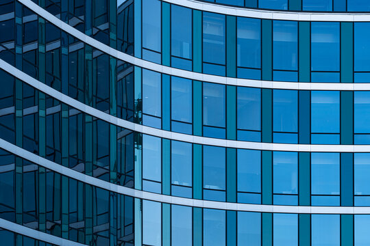 Blue glass building facade with windows and curves showing modern corporate architecture pattern and abstract design for urban headquarters background