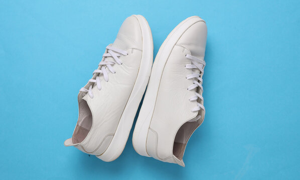 Classic white leather low-top sneakers on a blue background