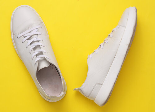 Classic white leather low-top sneaker on yellow background