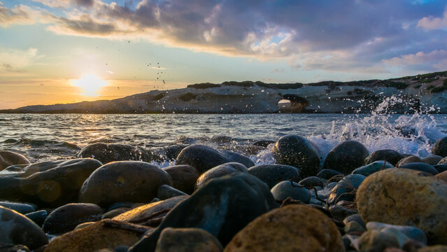 Sunset view of S'Archittu arch-shaped rock, forged by the sea and wind, from the beach in S'Archittu village, Sardinia Island, Italy