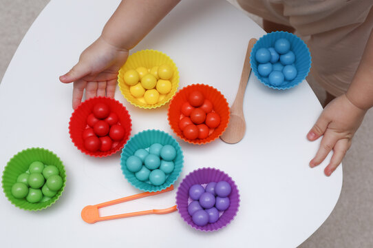 Little baby play with Color sorter,  balls and plates on a table. Developing motor skills and color differences.