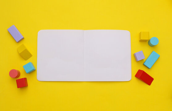 Mockup of white open children's book and toys on yellow background