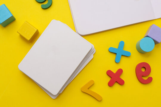 Mockup of white cards, baby toys on yellow background. Flat lay