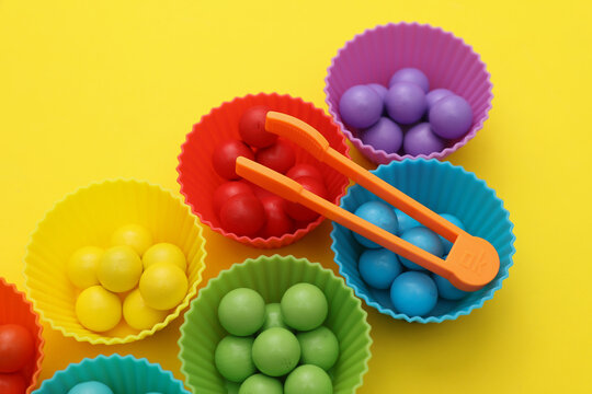 Game for little baby, developing motor skills and color differences. Color sorter with balls and plates on yellow background