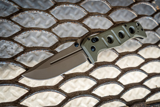 Military folding knife on steel grate