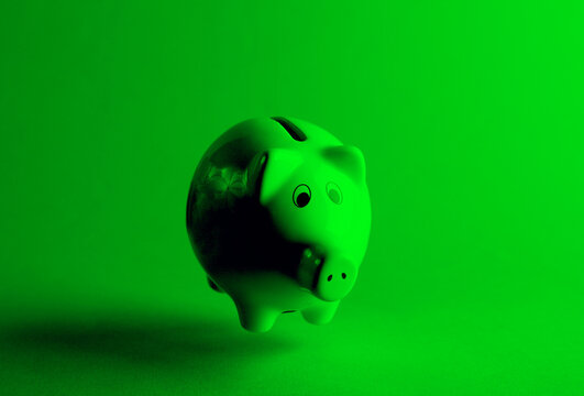 Floating piggy bank in green neon light