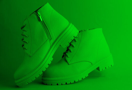 White leather boots in green neon light. Creative fashion still life