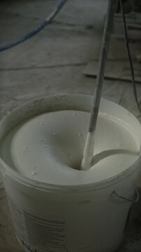 Mixing white wall putty in a bucket for home renovation