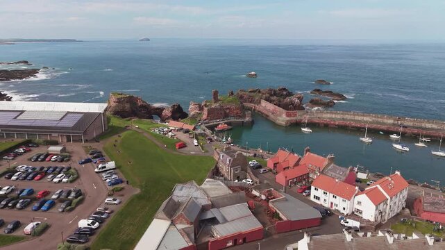 Aerial view of Dunbar coastal town with traditional red roof houses and historic castle ruins, Scotland.