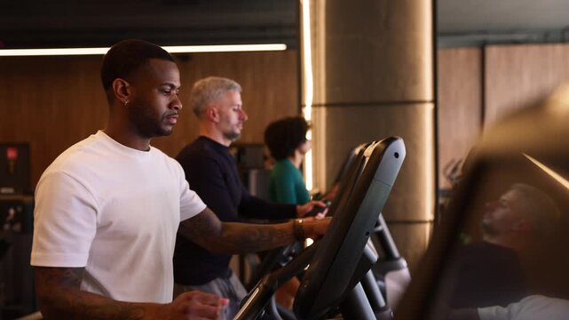 Multiethnic group of people training on elliptical machines at the gym