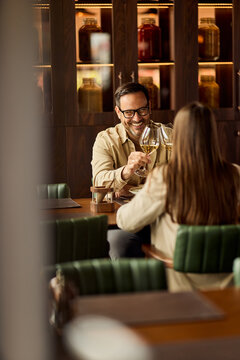 Smiling Man Toasting Wine With Partner During Cozy Date At Upscale Restaurant, Conversation And Connection