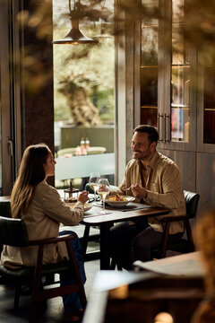 Happy Couple Enjoying Casual Dinner Date and Conversation in Modern Restaurant Over Wine
