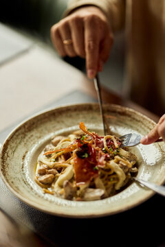 Hands Sharing Gourmet Pasta Dish In Cozy Italian Restaurant Dining Experience With Friends