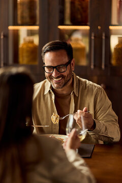 Smiling Man Sharing Pasta and Wine During Intimate Date Night Dinner at Cozy Restaurant
