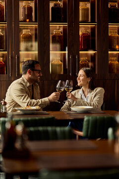 Couple Toasting With Wine Over Dinner in Upscale Restaurant During Casual Business Date