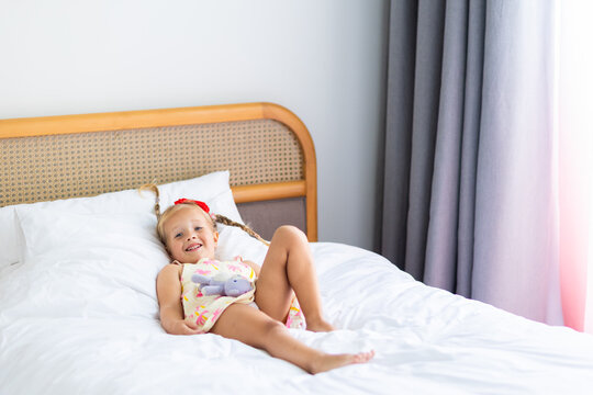 Smiling child lying on a bed with a stuffed animal