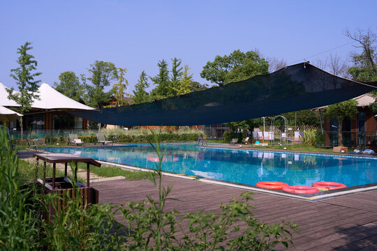 Sunny outdoor swimming pool with shade sail and wooden deck