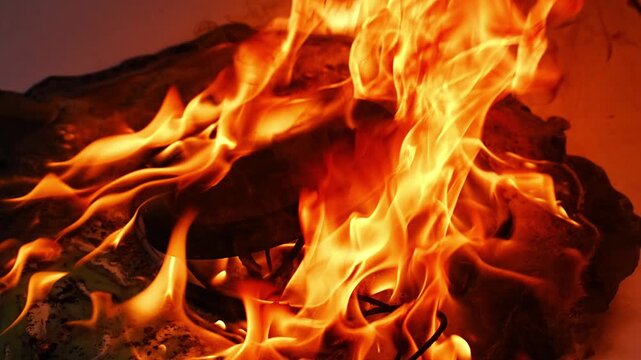 A melted plastic electric kettle engulfed in flames, with the fire brightly illuminating its surface and rising upward. a dangerous situation, with dense tongues of fire covering its body.