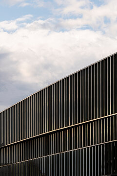 Pattern texture and lines define a modern urban architecture building facade under sky and clouds providing minimal editorial copy space background