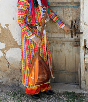 An Anatolian woman in local attire, holding a Turkish instrument called the bağlama (saz).