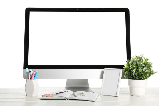 Table with blank computer monitor, frame and notebook isolated on white background