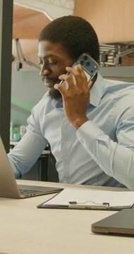 Black support specialist speaking on phone and checking notes