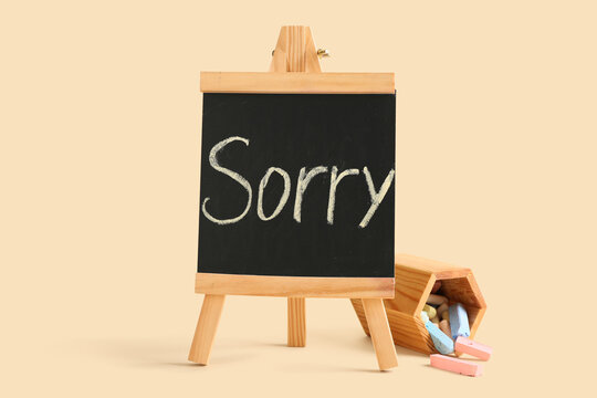 Easel with word SORRY written on chalkboard against beige background