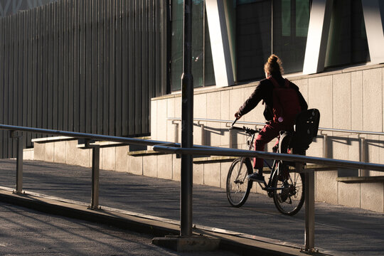 A modern urban pathway in Stockholm Sweden shows a cyclist on a bicycle using infrastructure for commute mobility through the city