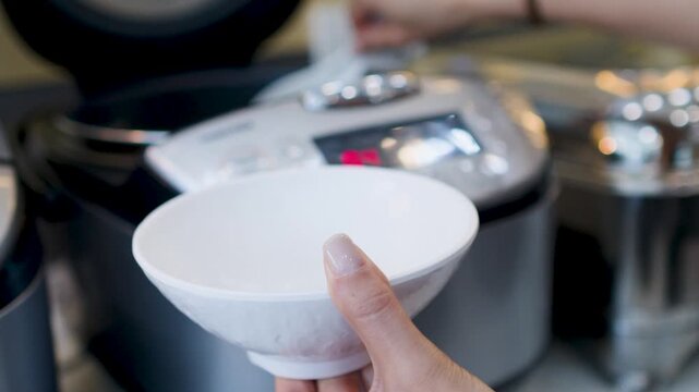 Hand Serving Rice from a Steamer into a White Bowl at Restaurant